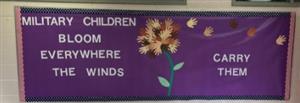 Text: Military Children Bloom Everywhere the Winds Carry Them on purple paper. Hand cutouts to make dandelion flower.