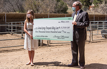  Jordyn Maisano, PPEC freshman, and Mayor John Suthers present a check to a local riding center. 