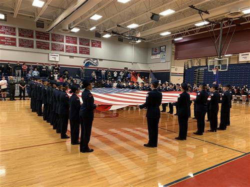 Sand Creek and Falcon cadets hold big flag before game. 